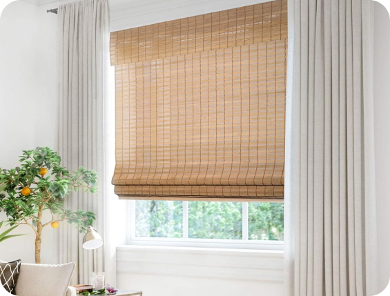 Bamboo Roman shades dress a sunlit window above a wooden table.