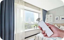 A hand uses a remote to control smart curtains in a modern bedroom.